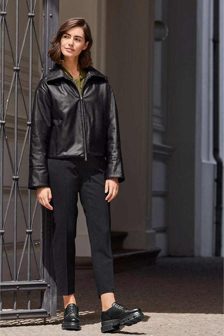 Femme en veste réversible en agneau noir avec col montant.