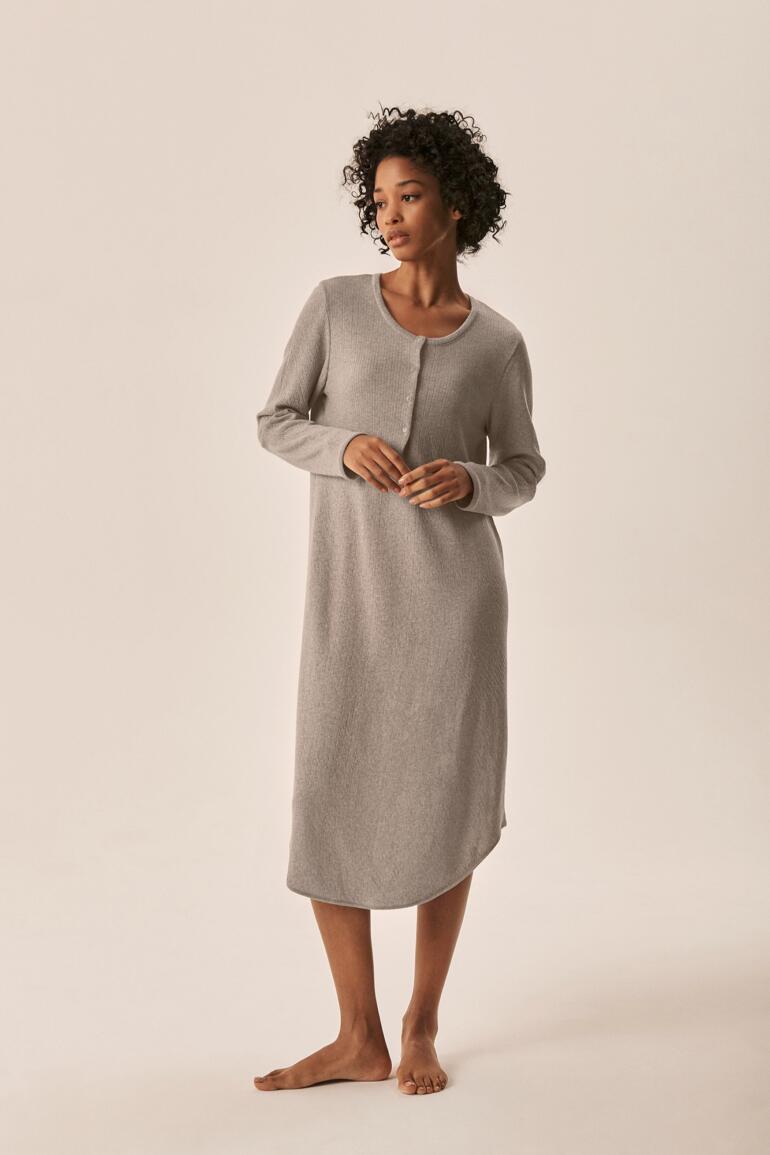 Femme en robe de nuit grise se tenant de face avec des manches longues.