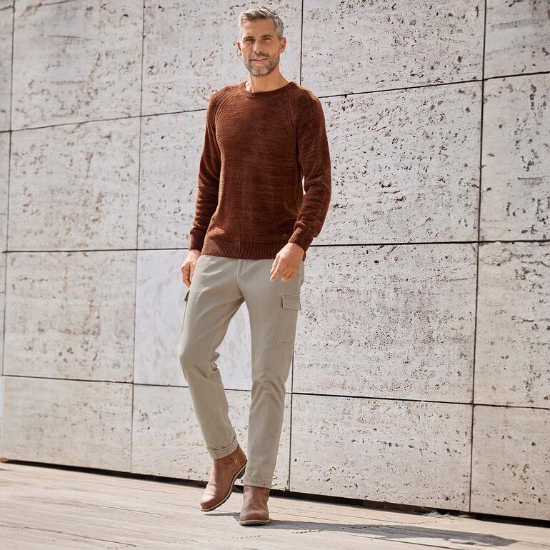 Pantalon cargo Dobby Homme portant un pull brun et un pantalon cargo beige Dobby devant un mur texturé.