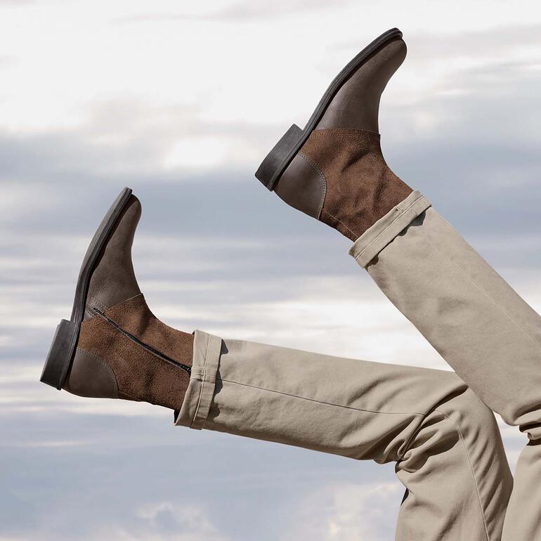 Bottes en cuir de buffle marron tenues en l'air avec les pieds