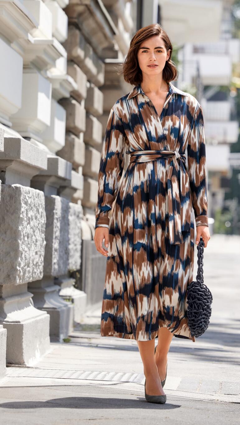 Robe flatteuse Everyday Femme dans une robe flatteuse avec un motif coloré et une ceinture dans la rue.