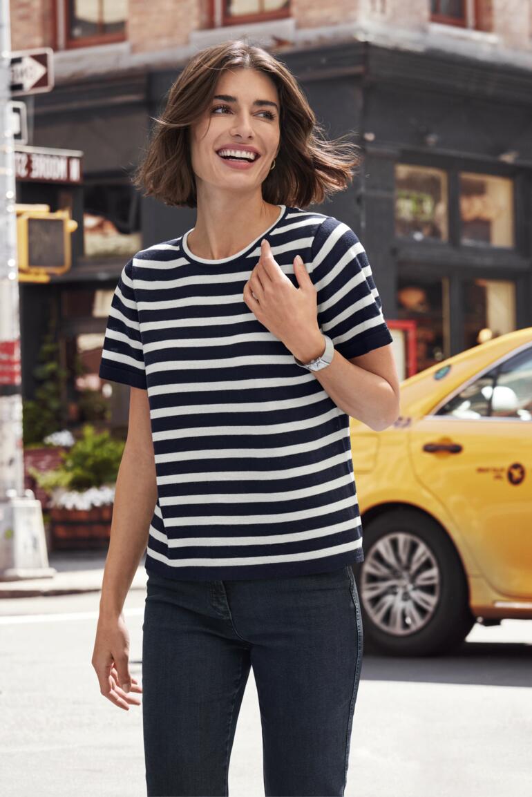 Femme portant un t-shirt à rayures en merino et souriant.