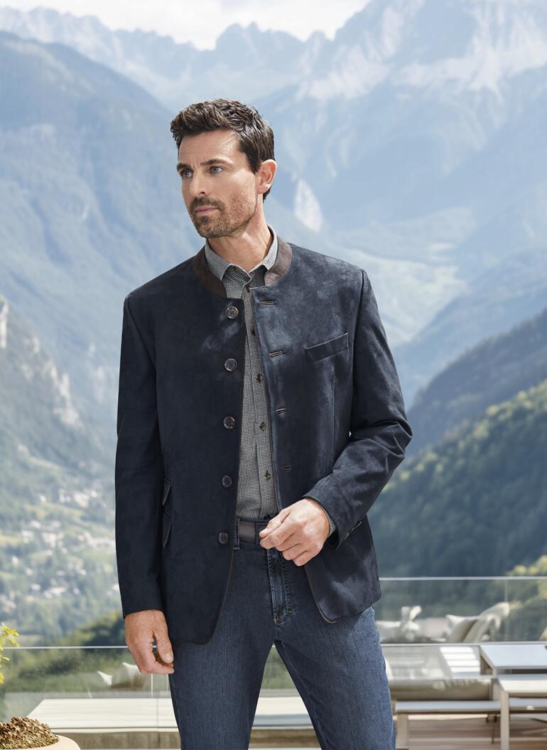 Homme en vest en velours bleu marine devant le paysage alpin.