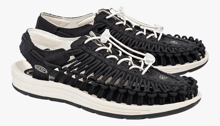 Une paire de sandales Uneek de KEEN en noir et blanc sur fond blanc.