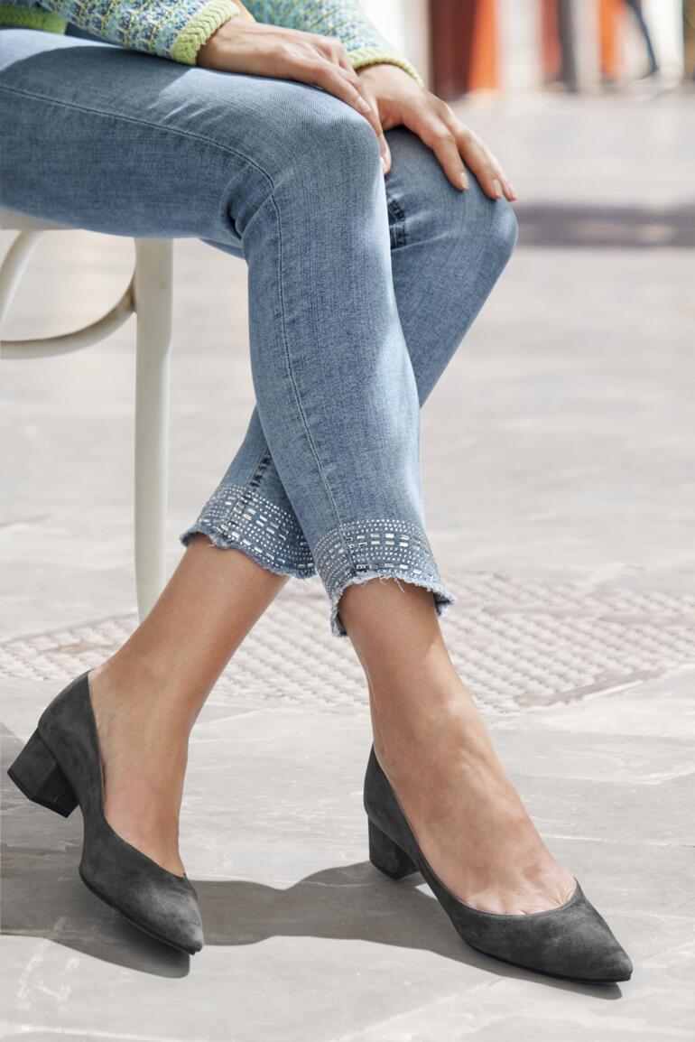 Femme portant des chaussures grises avec des jeans déchirés.