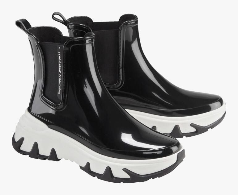 Bottes Chelsea noires avec des semelles blanches, placées par paires sur fond blanc.