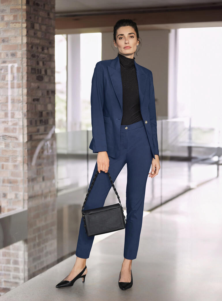 Femme en costume stretch bleu avec un sac noir.