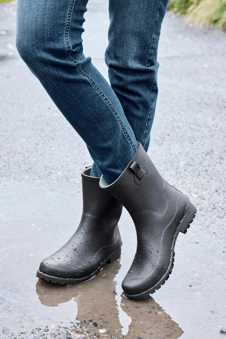 Bottes en caoutchouc noires de Green Comfort, se tenant dans une flaque.