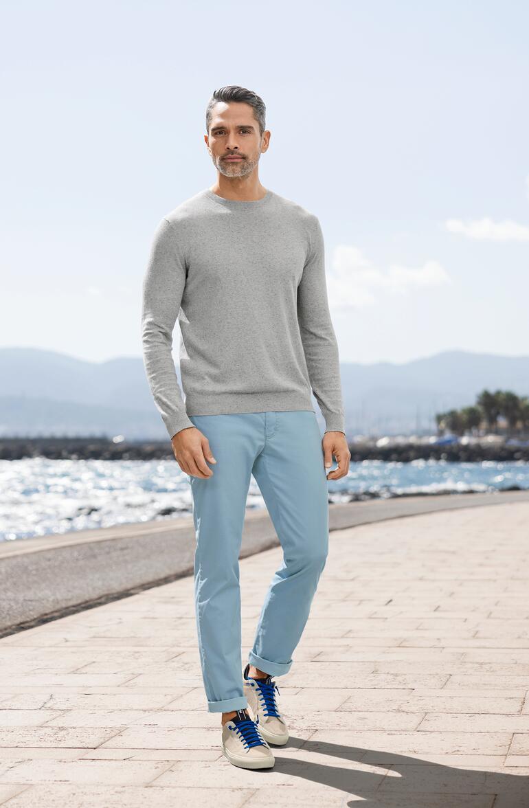 Gris Homme en pull en tweed d'été gris et pantalon bleu sur la plage.