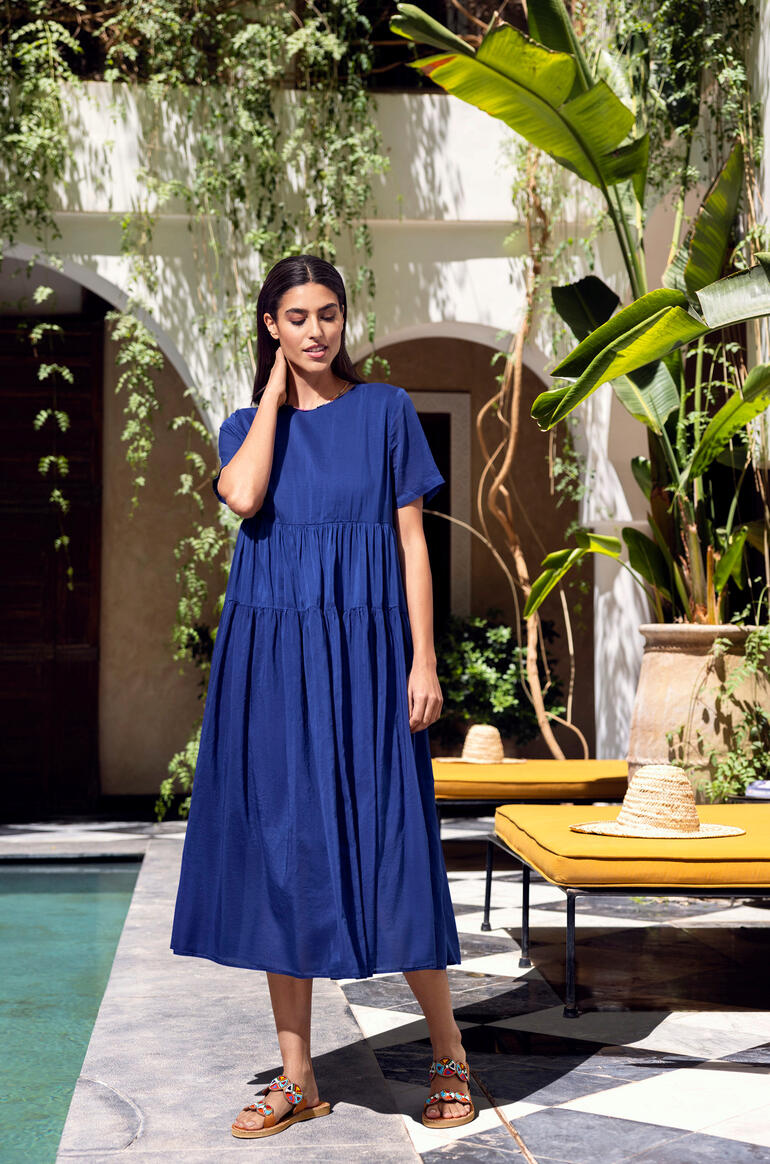 Femme en robe d'été bleue se tient devant un décor élégant