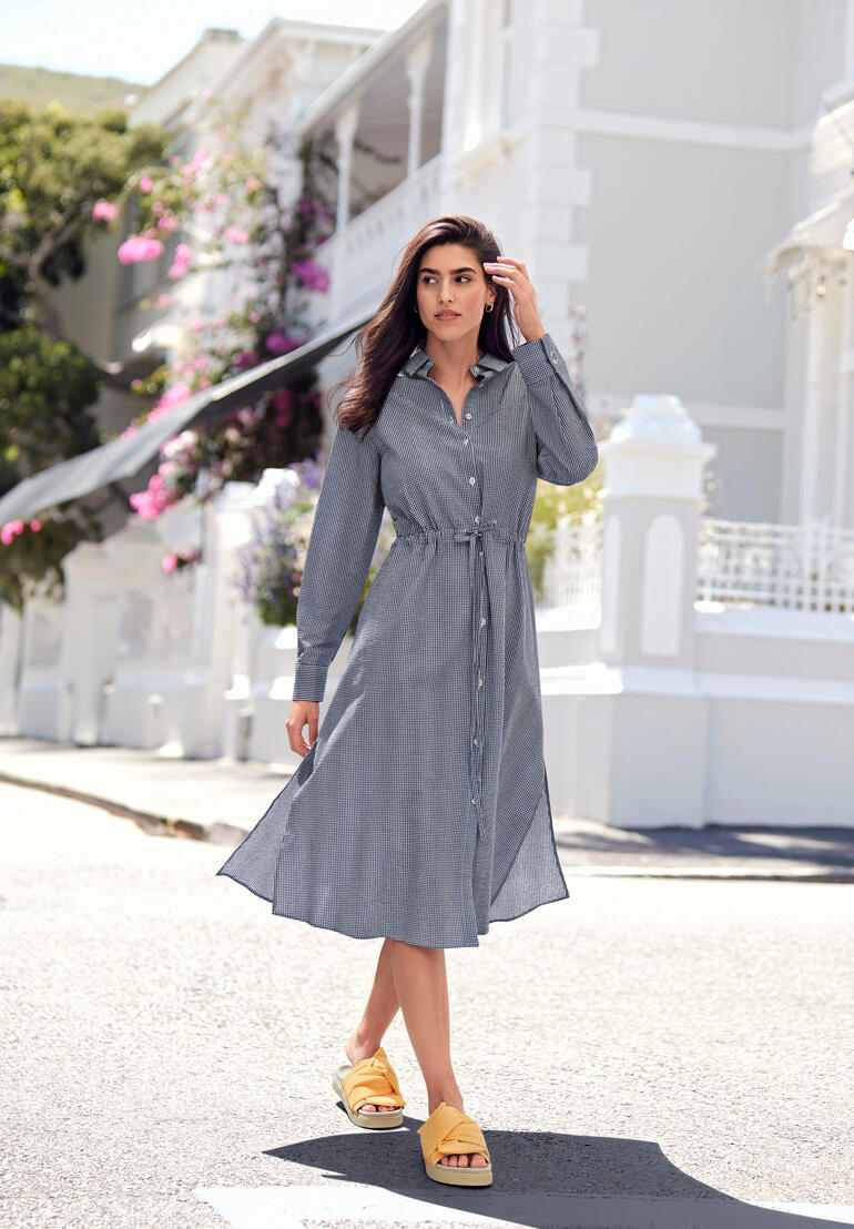 Femme en robe à carreaux seersucker avec ceinture, debout dans la rue