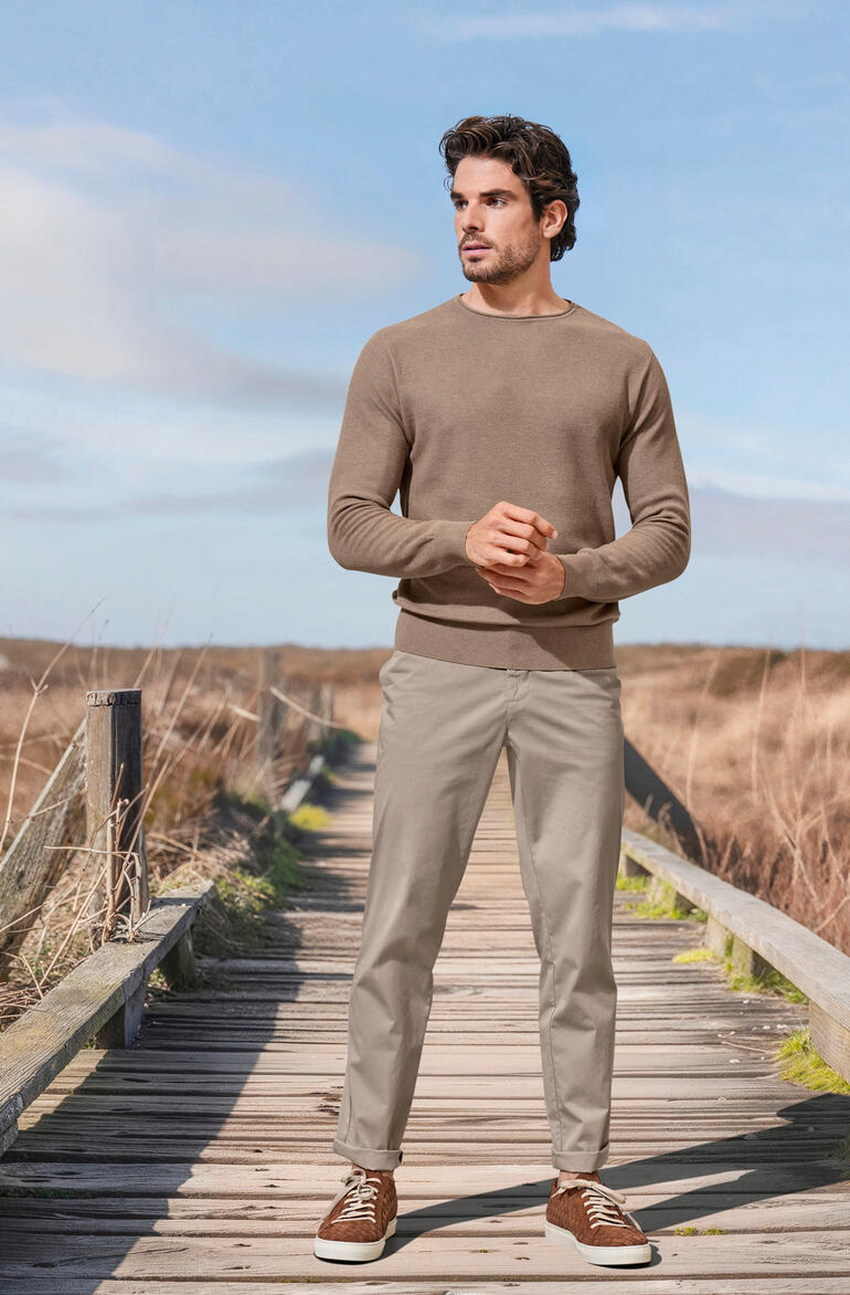 Taupe Homme en pull beige et pantalons clairs sur un chemin en bois