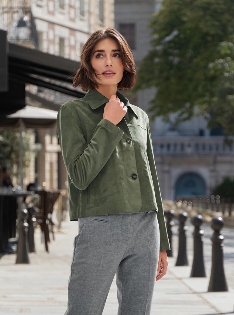 Femme en veste en cuir verte avec jean dans un environnement urbain