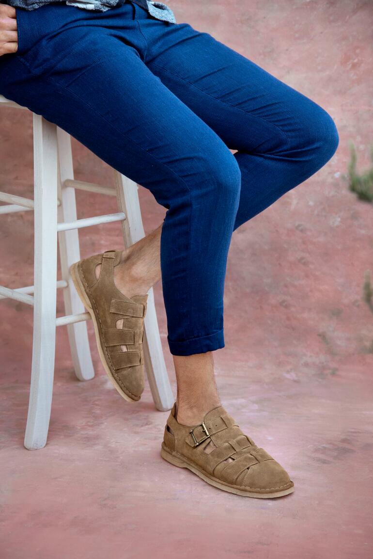 Sandales de boulanger luxueuses Sandales de boulanger luxe en brun, associées à un pantalon bleu.