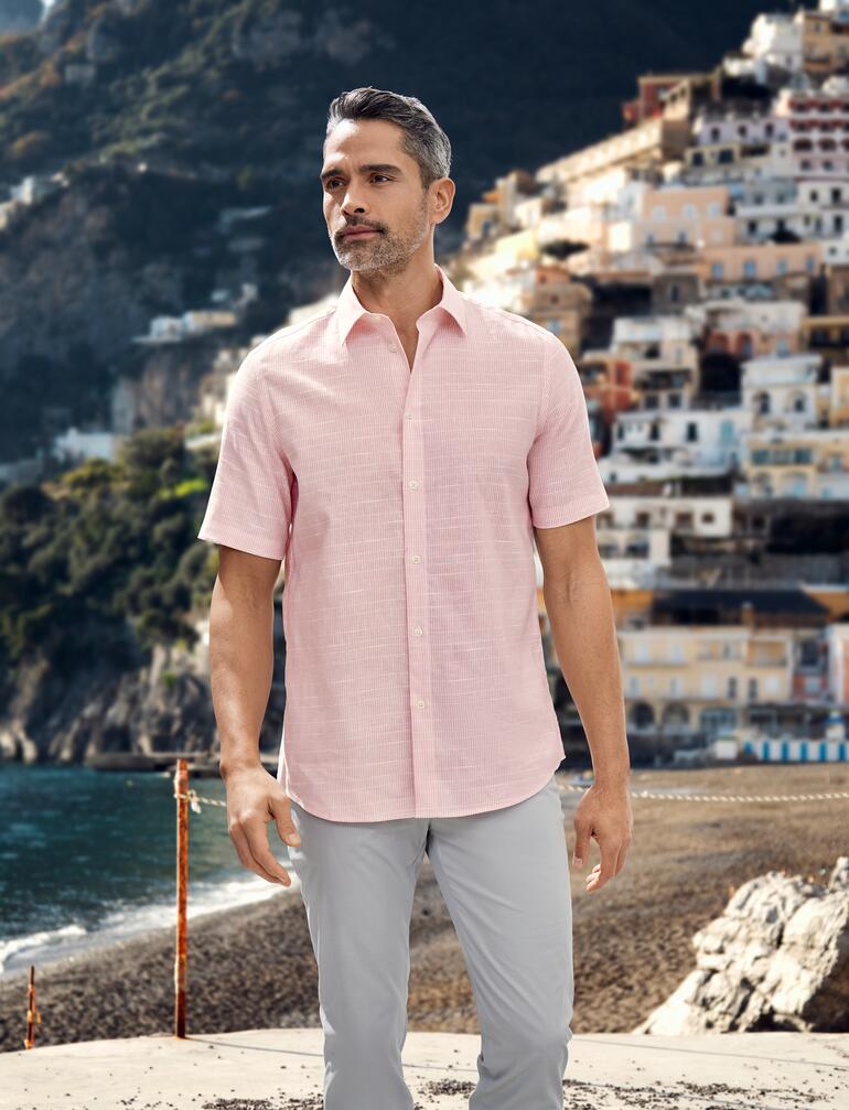 Homme portant une chemise tropicale rose sur la plage.