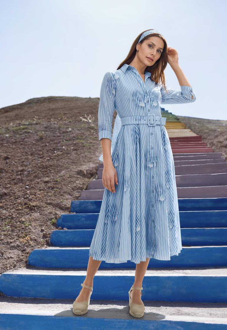 Robe rayée bleue avec fermeture à boutons et ceinture portée par une femme.