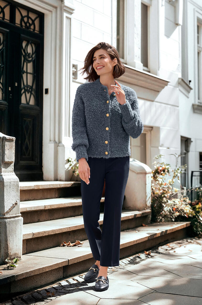 Femme en cardigan en alpaga bouclé gris sur un escalier.