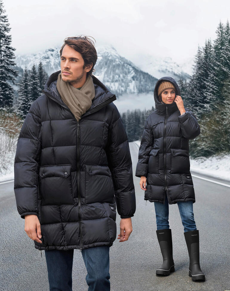 Parka en duvet Taion sur deux personnes dans un paysage d'hiver neigeux.
