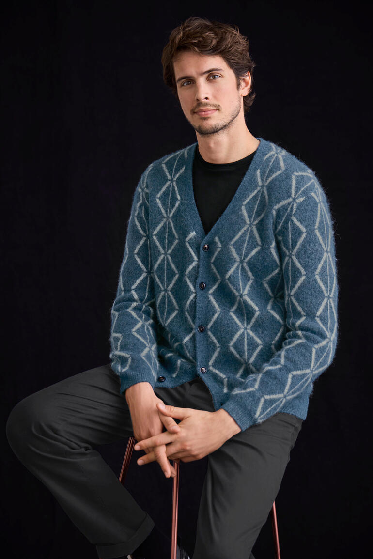 Cardigan en alpaga brossé Homme assis dans un cardigan en alpaga brossé bleu avec un motif losange.