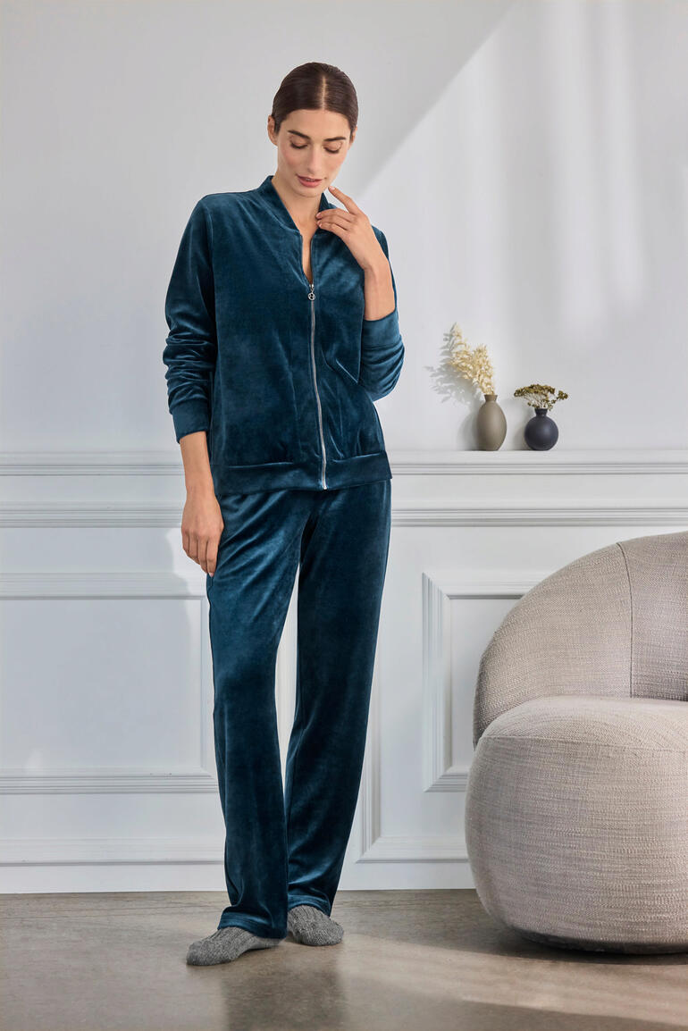 Femme portant un ensemble en velours Hanro vert, détendue dans un environnement moderne.