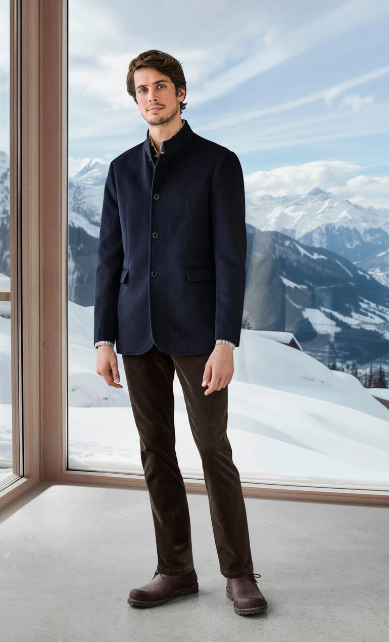 Homme portant un blazer en baby alpaga bleu marine devant un paysage de montagne