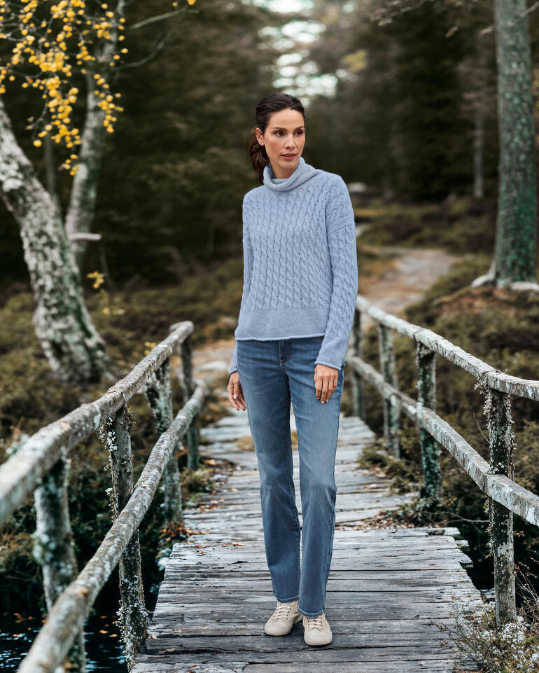 Femme en pull en tricot bleu et jean sur un pont en bois dans les bois