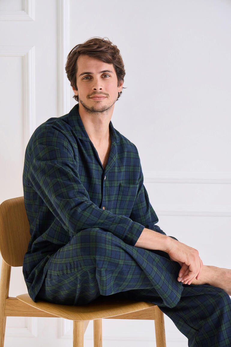 Homme en pyjama en flanelle à carreaux, assis sur une chaise.