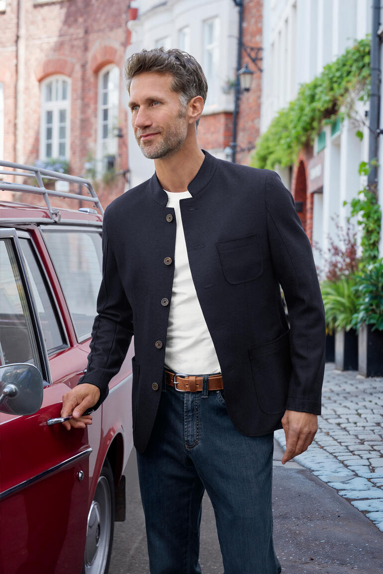 Veste casual pour hommes en noir, portée par un homme devant un vieux bâtiment.