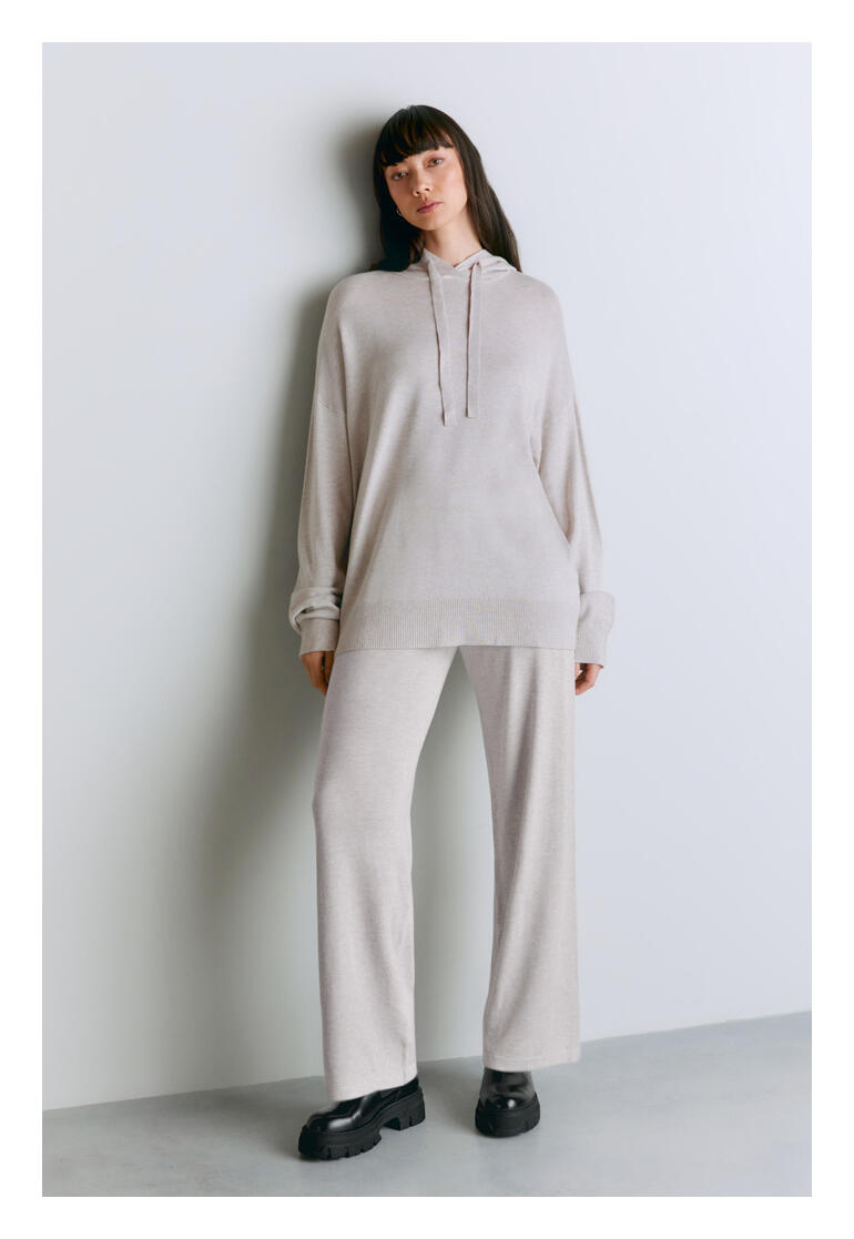Sweat à capuche en Lyocell/cachemire Femme portant un hoodie en lyocell/cachemire gris clair, debout devant un mur.