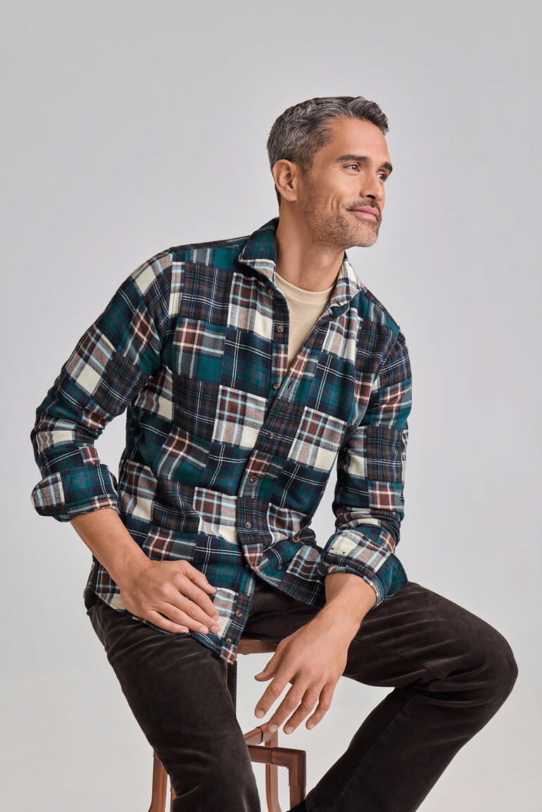 Chemise en flanelle Patchwork DU4 Homme portant une chemise en flanelle patchwork DU4 à carreaux, assis sur un tabouret.