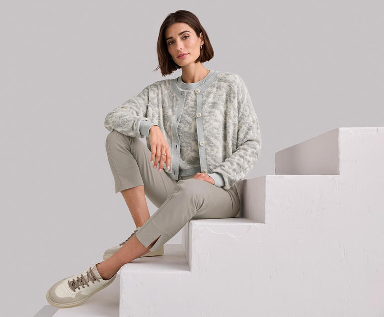 Pull et Cardigan Femme assise sur une marche, portant un twinset en jacquard 3D gris.