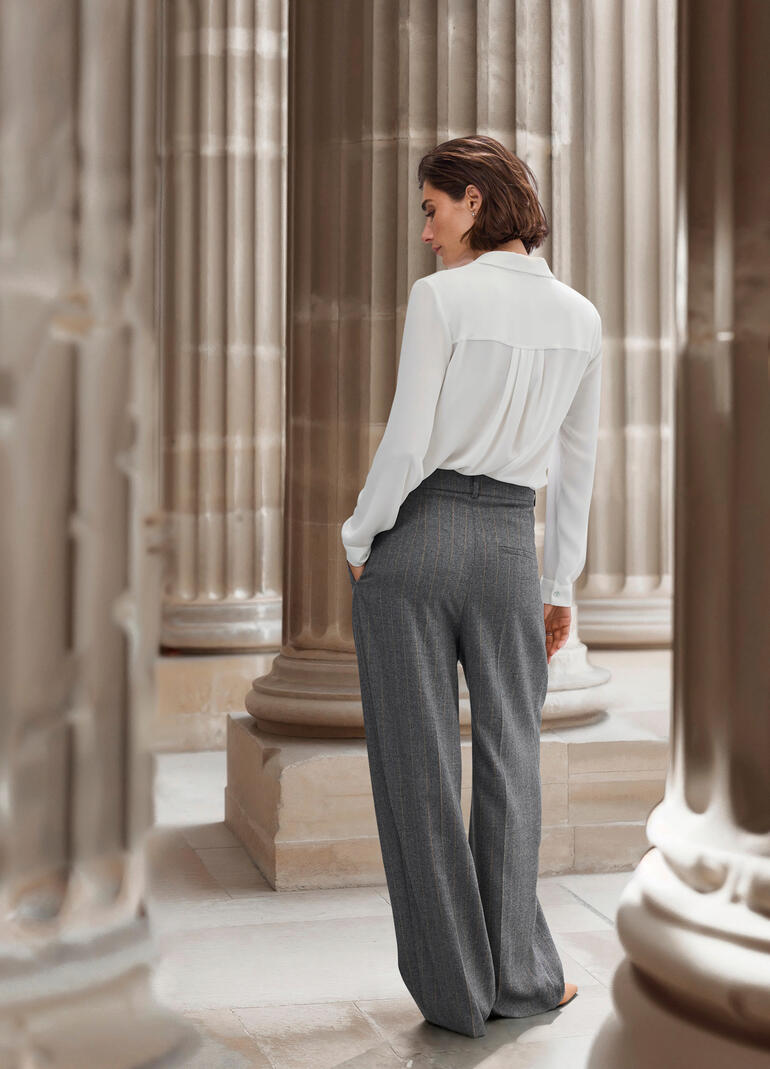 Femme vue de dos dans une tenue élégante, montrant le pantalon à rayures.