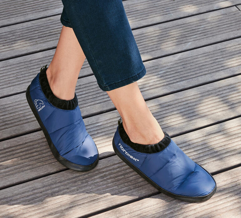 Chaussure en duvet Nordisk bleue, portée par une personne sur un sol en bois.