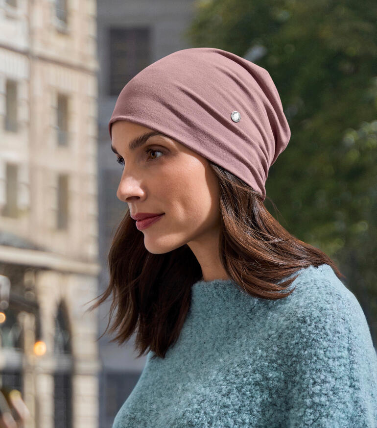 Bois de rose Beanie en bambou rose, portée par une femme dans un pull bleu.