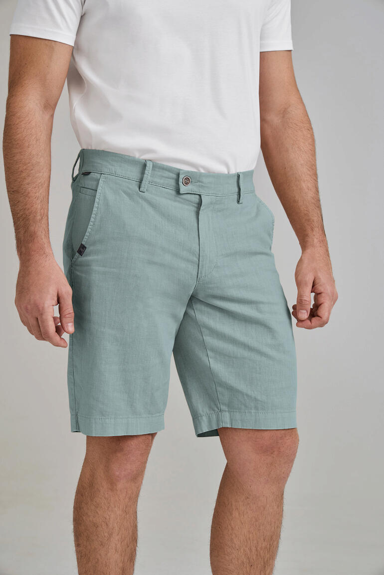 Homme debout en bermudas en lin business vert clair