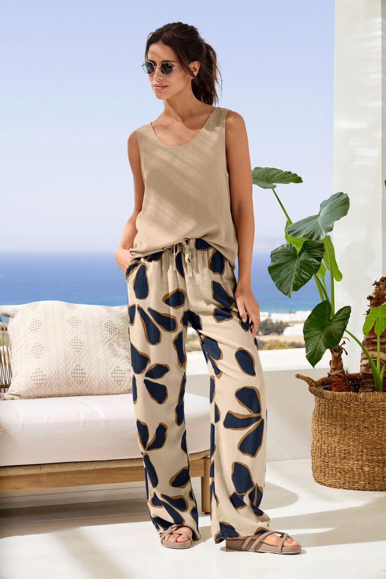 Femme en loungewear urbaine décontractée avec un haut beige et un pantalon à motifs sur une terrasse