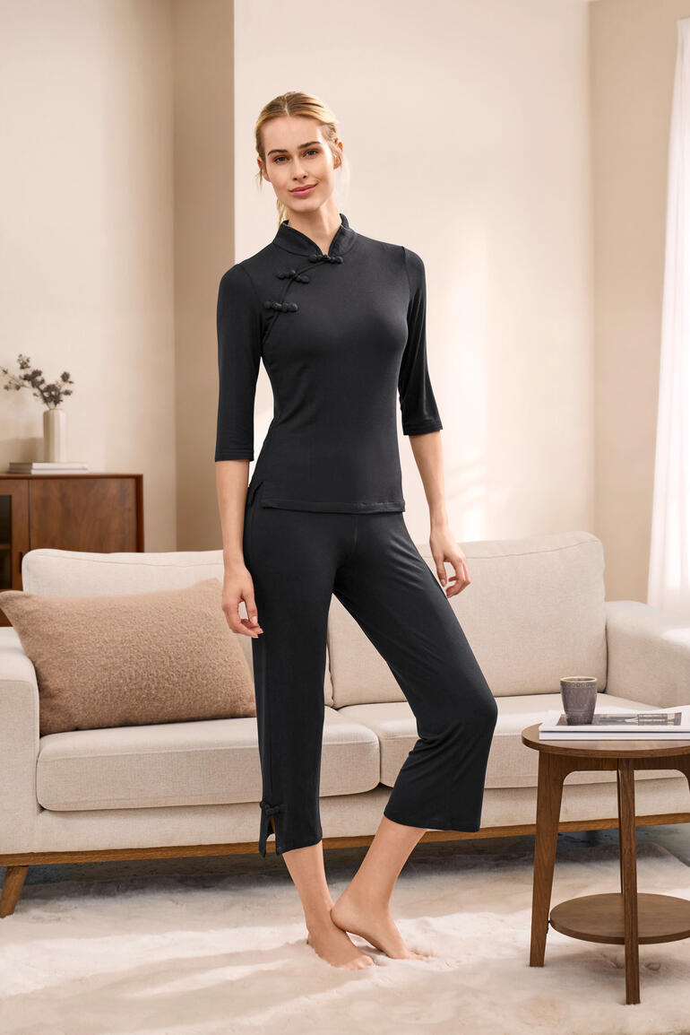 Femme en pyjama Dreamsack noir à manches longues se tient dans un salon.