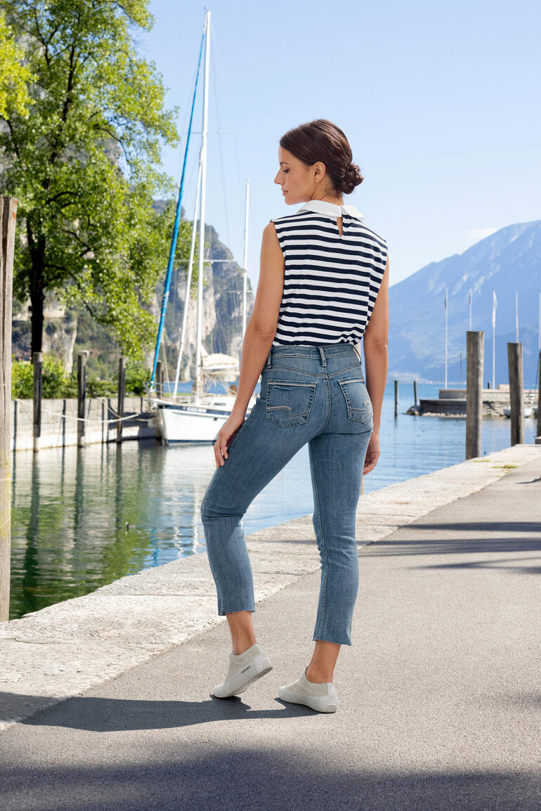 Jeans Suki Straight Silver Femme en haut rayé et jean sur un trottoir au bord de l'eau.