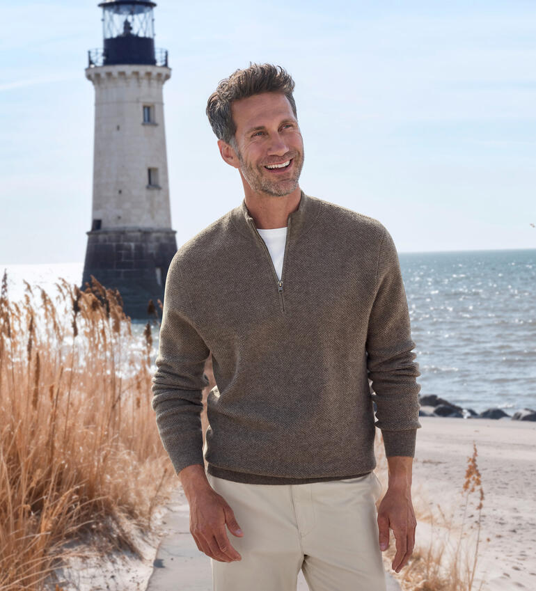 Homme portant un pull près d'un phare au bord de la mer