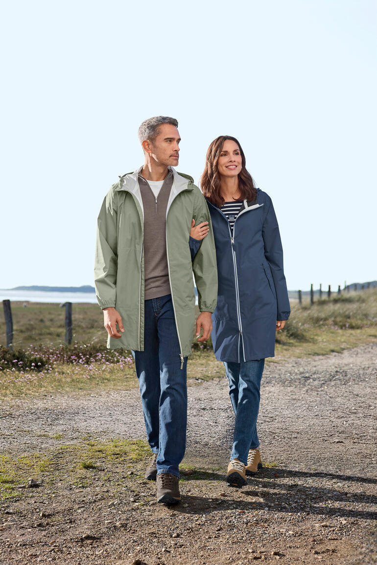Sauge et Bleu poudre Couple en vestes imperméables se promène le long d'un chemin.