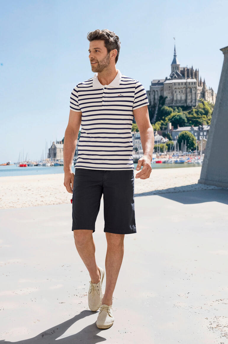 Polo de Bretagne Saint James Homme en polo à rayures Saint James Bretagne, marchant sur la plage.