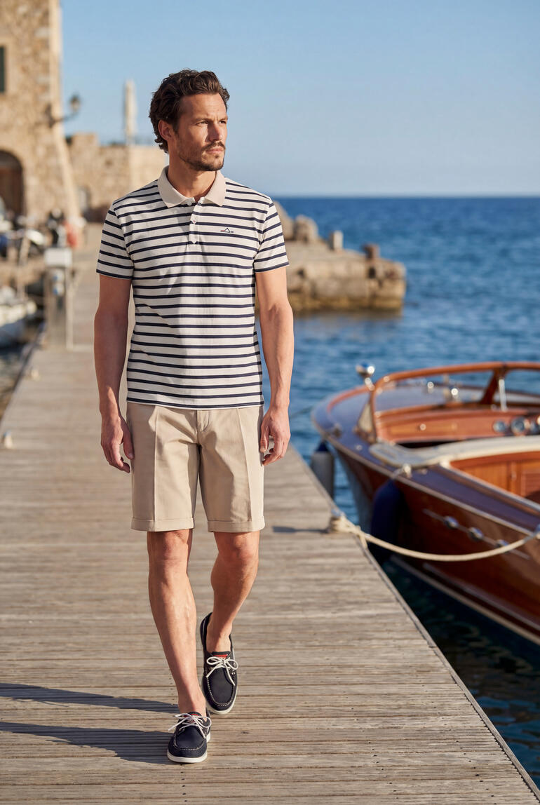 Homme portant un polo rayé et un short au port.