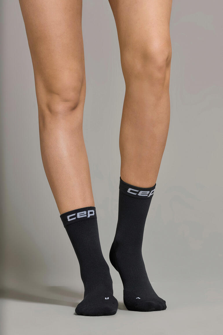 Chaussette de sport noire Core, visible sur un pied, de face.