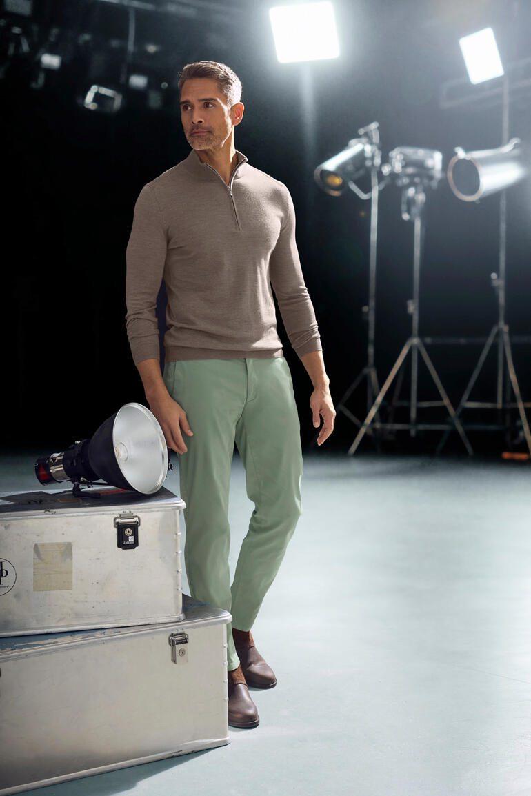 Homme portant un chino se tenant dans un studio.