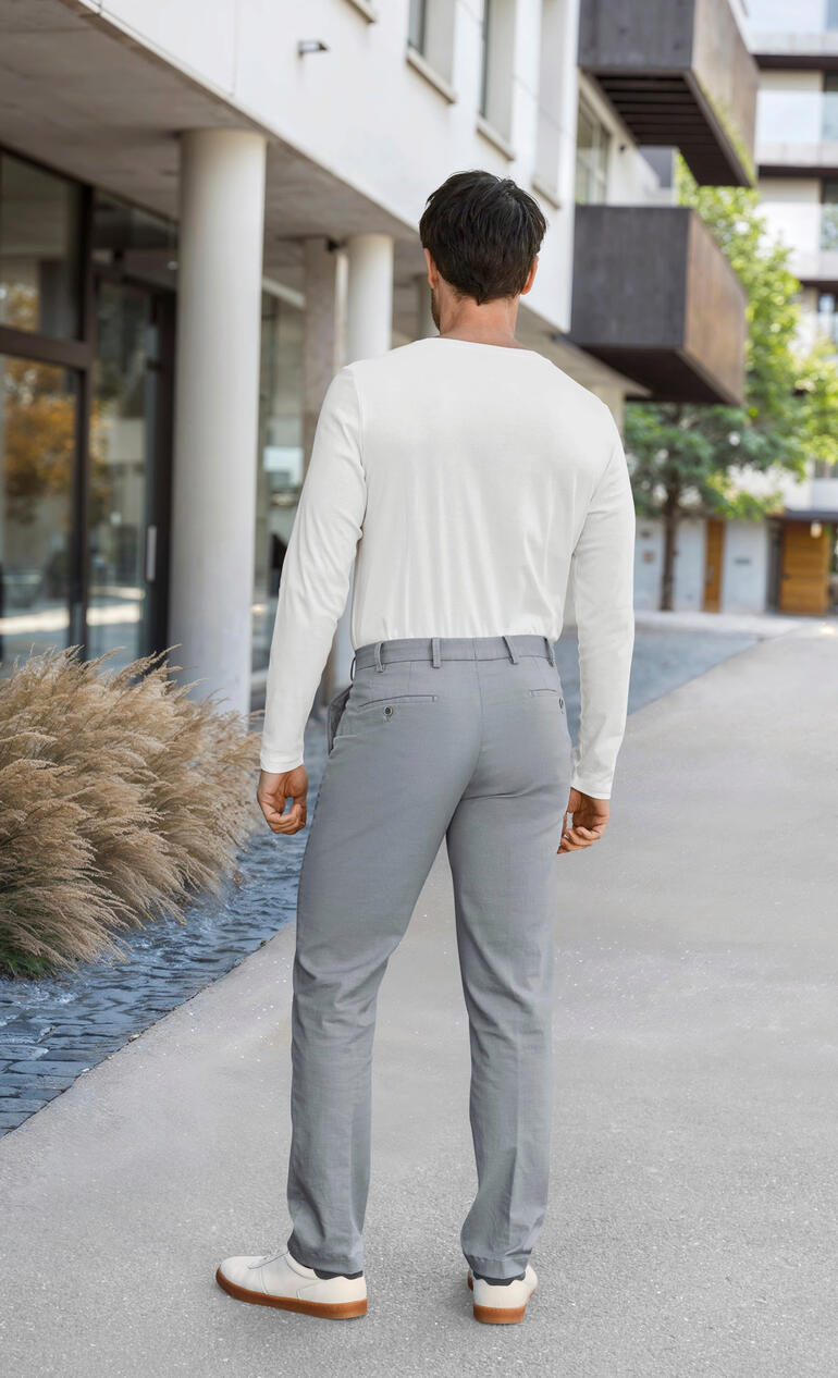 Homme en haut blanc et pantalon gris, vu de dos.