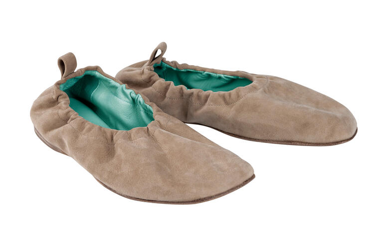 Ballerines élastiques brunes sur fond blanc, douces et flexibles.