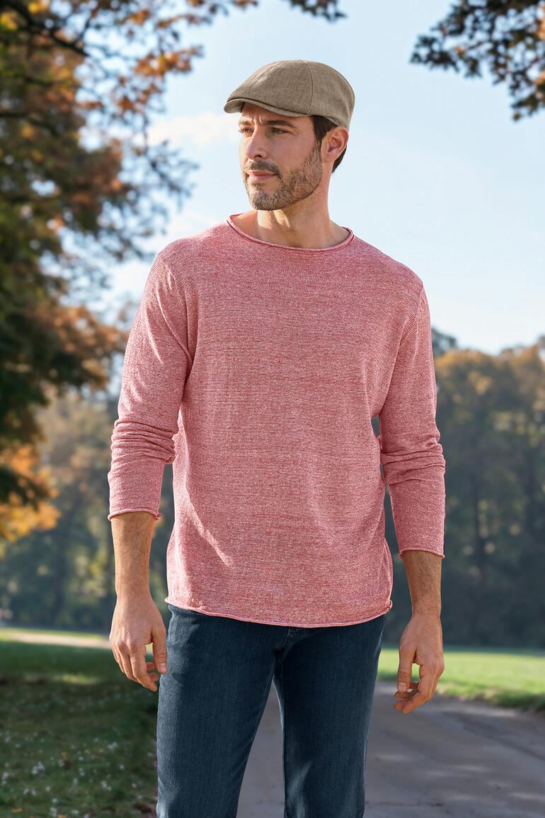 Homme en pull rouge avec manches longues et casquette dans la nature.
