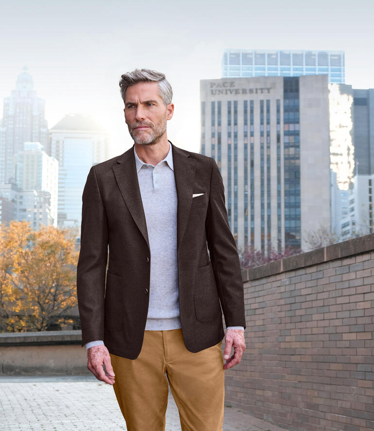 Homme en blazer marron marche dans un environnement urbain.
