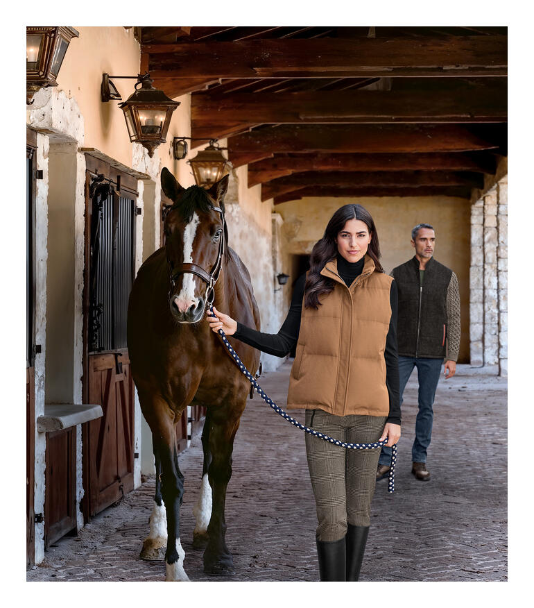 Gilet en mélange de laine camel, modèle tenant un cheval en laisse.