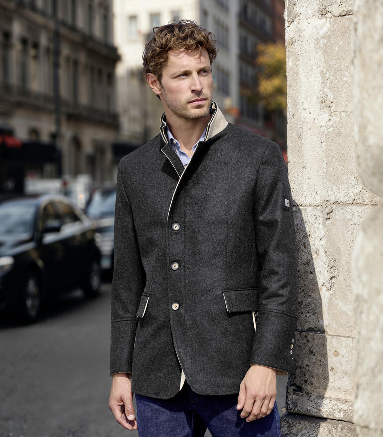 Homme en manteau en loden mérinos adossé à un mur dans la ville